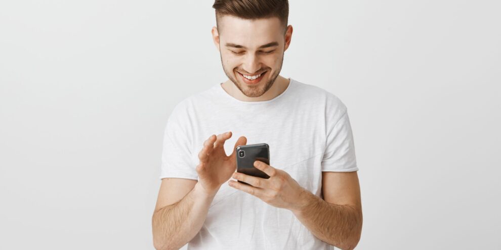 smiling-happy-young-man-using-mobile-phone-messaging-with-smartphone-scaled